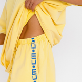Yellow lounge shorts with drawstring waist and blue CW logo detail - pockets – close up side view