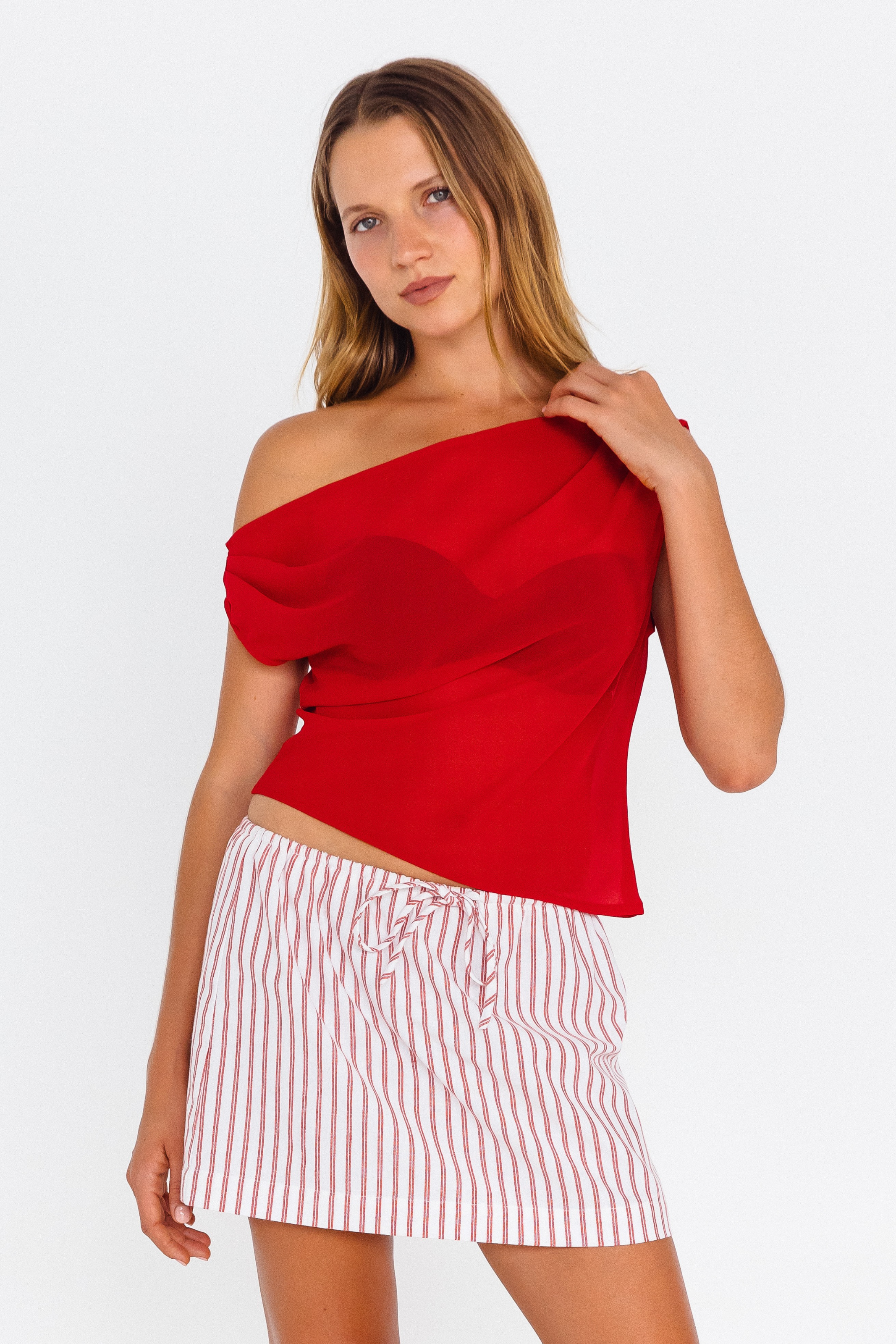 Red off-shoulder fitted top – front view worn with white striped mini skirt - close up image